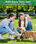 Two girls playing with a dog on green lawn, wearing Heavy Duty Lawn Aerator Shoes With Spikes Easy Wear Hook And Loop Straps Preassembled.