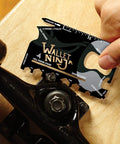 18 Tools In One Credit Card Sized Multitool For Quick Fixes And Everyday Carry being used on a skateboard, compact black gadget.