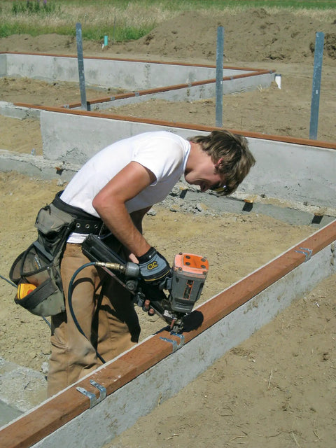 Worker using a nail gun with N10DHDGPT2500 Strong-Drive 33 SCN Smooth-Shank Connector Nail Two And One-Half Inch HDG on framing