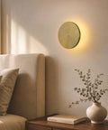 DANCYHOME 6.7" Rechargeable LED Wall Sconce in Brushed Brass, mounted on wall near a bed, providing ambient lighting.