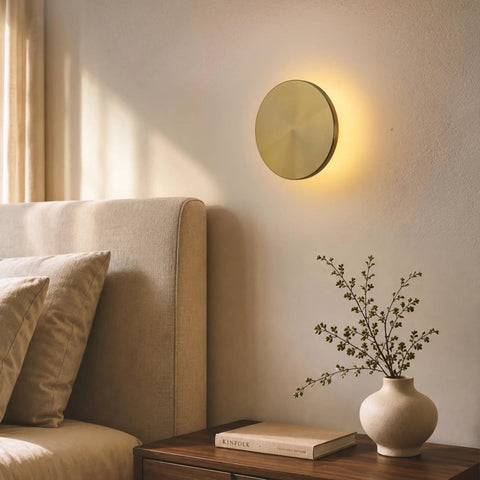 DANCYHOME 6.7" Rechargeable LED Wall Sconce in Brushed Brass, mounted on wall near a bed, providing ambient lighting.