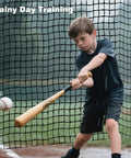 Child practicing baseball with Heavy Duty Square Batting Cage Net for Baseball and Softball Training in wet conditions.