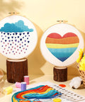 Five Piece Starter Embroidery Kit For Beginners With Boho Cross Stitch Patterns, Two Embroidery Hoops, Floss, Needles, Thread Guide, And Step By Step Instructions For DIY Rainbow Themed Projects displayed with colorful patterns.