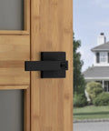 Keyed Entry Door Handle Lock Matte Black Exterior Reversible Lever on wooden door with house in background