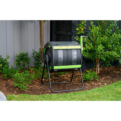 Dual Compartment 48 Gallon Compost Tumbler With Easy Turning Geared Design placed in a garden setting for composting.