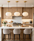 Vaziden Milk Glass Pendant Lights Kitchen Island Gold Chandelier 11.81" hanging above a marble kitchen island with seating.