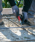 QLT Pull Tie Wire Twister For Concrete And Rebar Tying Contractor Tool in use with red rubber grip handle on construction site.