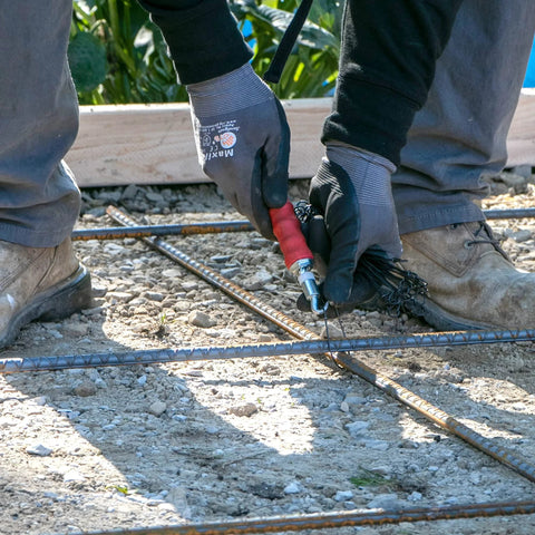 QLT Pull Tie Wire Twister For Concrete And Rebar Tying Contractor Tool in use with red rubber grip handle on construction site.