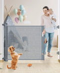 Mother with child and dog near 70 inch wide retractable baby gate with 33 inch height, upgraded safety double snap mesh gate for indoors.
