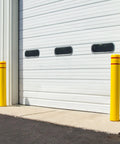 High Density Polyethylene Safety Bollard Covers Refresh Rusty Outposts With Zero Sweat Installation Plus Included Foam Pad For A Snug Setup Blocks Scratches On Pavement While Keeping The Area Looking Clean Without Any Extra Drama Year Round. Yellow bollard covers near a garage door.