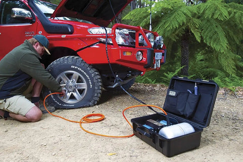 Heavy Duty Road Trip Ready 12 Volt Twin Motor Portable Air Compressor in use on off-road truck tire.