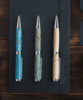 Knockout Twenty Piece 7Mm Slimline Twist Pen Kit With Shiny Silver Refills; three custom pens with silver accents on a black notebook.
