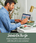 Man using Salad On The Go Meal Prep Kit With 54 Oz Bowl Four Compartment Toppings Tray Leak Proof Dressing Container Reusable Fork BPA Free Lunch Box Removable Bento Tray Khaki Green at desk.
