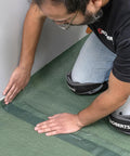 Installation of Real Deal 3 In 1 Flooring Underlayment Roll For Laminate And Engineered Wood smoothing edges against a wall.