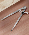 Heavy Duty Six Inch Alloy Metal Compass Scribe Dead Nuts Accurate Layout Divider For Precise Woodworking Marking And Measuring On Plastic Wood Or Steel Panels on a wooden surface.