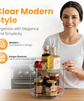 Front view of a clear two-tier lazy Susan organizer on a kitchen counter with spice jars.