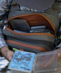 Person accessing Cross Current Chest Pack For Fly Fishing Gear, Durable 210D Nylon Cyclepond Fabric, showing large main compartment.