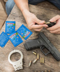 100 Pack Lead Remover Wipes for Shooting Ranges and Industrial Cleaning with firearm, bullets, and handcuffs on wooden table