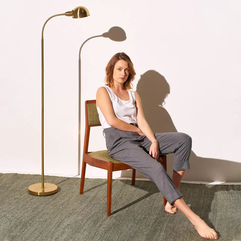 Woman seated beside Slim LED Floor Lamp With Adjustable Gooseneck Free Standing Corner Pole Light in Brass Gold Finish
