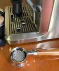 58Mm Bottomless Portafilter With Wooden Handle Compatible With Breville Espresso Machines BES900XL BES920XL BES980XL BES990BSS on wooden table.