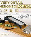 Gramercy adjustable mandoline slicer on a wooden board; black body with stainless blade, sliced cucumbers nearby, gloves