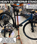 Beefed Up Heavy Duty Bike Repair Stand With Storage Bag Adjustable Height Up To 30 Inches 360 Degree Rotating Clamp Magnetic Tool Tray Telescoping Center Pole Perfect For Road Mountain Hybrid Or Commuter Bikes holding a bicycle in a shop