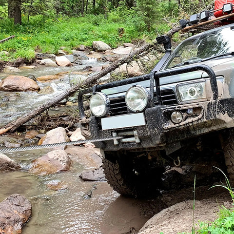 SUV using Beefy Heavy Duty 3/8 Inch By 100 Foot Steel Winch Cable With 15,200 Lbs Breaking Strength to cross rocky stream