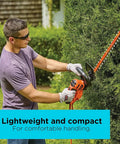 Person using 22 Inch Electric Hedge Trimmer With Dual Action Blades And Full Wraparound Handle in garden setting