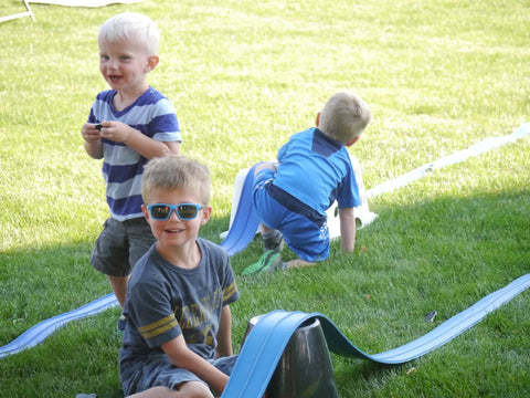 Children playing with Classic 15-Foot Race Track Starter Set With 2-Lane Wide Track, 2026 Upgrade For Smoother, Faster Runs on grass.