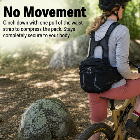 Cyclist wearing a Mountain Bike Hydration Pack With 3L Bladder And 10L Storage For Trail Rides, lumbar support, charcoal color.