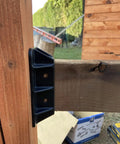 Close-up of Top Shelf Heavy Duty Privacy Fence Brackets For Standard 2x4 Wood Railings attached to wood railing, showing pre-drilled design.