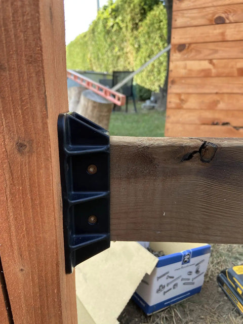 Close-up of Top Shelf Heavy Duty Privacy Fence Brackets For Standard 2x4 Wood Railings attached to wood railing, showing pre-drilled design.