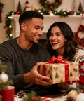 A couple exchanging a Christmas present in a cozy holiday-decorated living room, with a fireplace and festive decorations in the background.