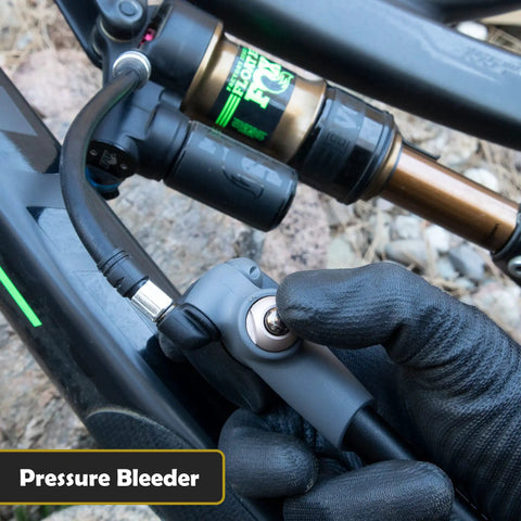 Cyclist using ShockPro MTB Shock Pump With 300 PSI High Pressure Gauge on mountain bike, showing pressure bleeder feature.