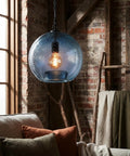 CASAMOTION Modern Farmhouse Blue Glass Globe Pendant Light 11" Dia hanging over a sofa with pillows and a textured background.