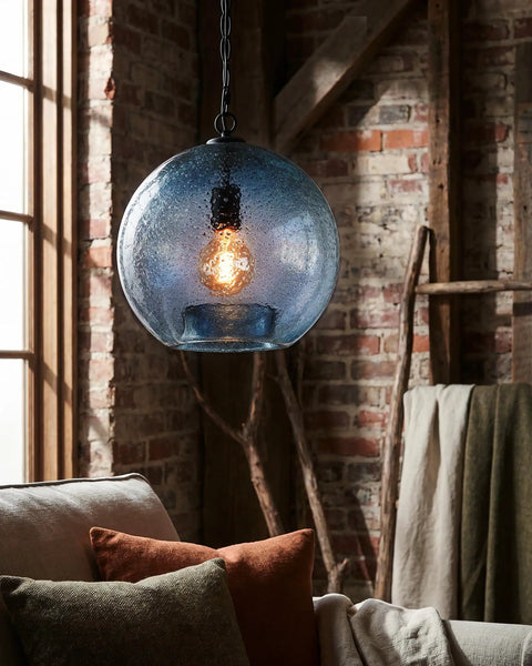 CASAMOTION Modern Farmhouse Blue Glass Globe Pendant Light 11" Dia hanging over a sofa with pillows and a textured background.