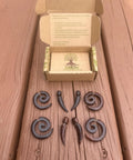 Spiral Fake Gauge Earrings Set In Black With Organic Wood And 316L Surgical Steel, showing two pairs on wood surface with box