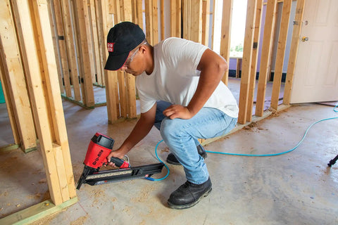 Person using nail gun with 21 Degree Exterior Galvanized Framing Nails For Wood-To-Wood Builds, Plastic Strip Collated Fasteners.