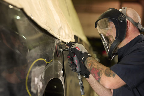 Mechanic using 5102MAX Air Die Grinder with Right Angle Head on vehicle surface, ergonomic grip visible, in repair shop.