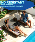 Heavy Duty 120Lb Fillable Umbrella Base With Wheels And Handle next to poolside loungers, offering shade from large blue umbrella.