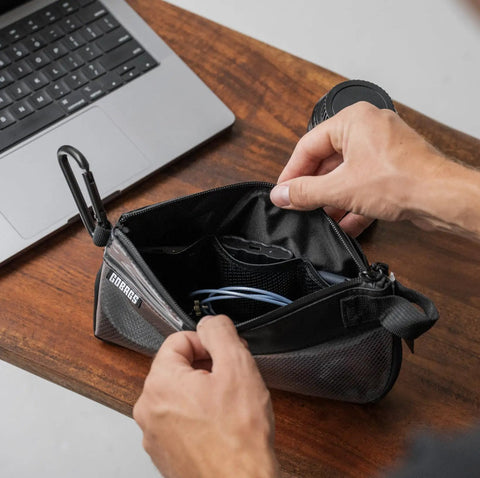 Person organizing cables in Small Black Electronics And Camera Accessories Bag With TPU Water Resistant Layer on table