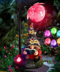 Colorful Gradient Solar LED Garden Gnome Statue for Outdoor Patio Balcony Yard Lawn Decor Gift Solar Powered Lighted Gnome Figurine with Vivid Night Glow, featuring a reading gnome under a pink glowing orb with colorful lights in the background, set in a garden path.