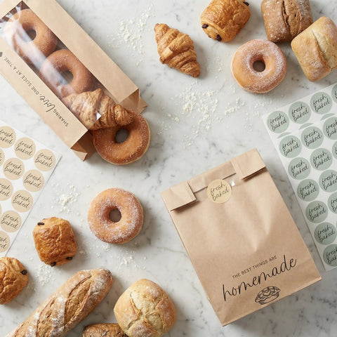Clear Window Bread Bags For Homemade Bread Keep Sourdough Fresh For Days And Make Gifting Your Bakes A Breeze Eco Friendly Kraft Paper Packaging For Bakery Goods shown with various breads and stickers on marble surface.