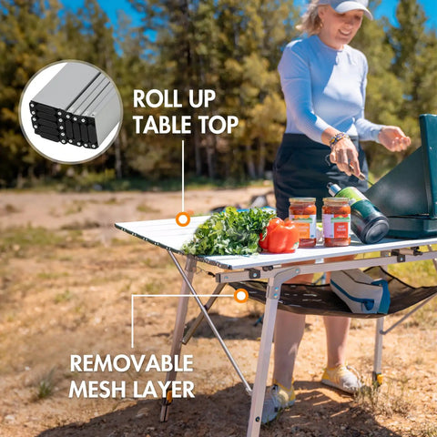 Portable Folding Camping Table With Adjustable Aluminum Legs in use at outdoor picnic, roll-up top, mesh storage visibly shown.
