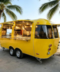 Kickass Commercial Stainless Steel Food Trailer With Integrated Air Conditioning Heavy Duty Mobile Kitchen Rig For Smokin Burgers And Quick Service Operation, yellow exterior, beachside setup.
