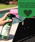 Hand applying Gear Hugger eco-friendly lubricant to a black metal grill with text promoting maintenance benefits.