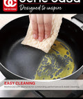 Hand wiping oil from Black Nonstick Aluminum Frying Pan With Glass Lid 6 Inch That Feels Like A Kitchen Workhorse For Quick Searing And No Fuss Food Release Dishwasher Safe Cleanup Durable Nonstick Coating Perfect For Weeknight Meals And Small Batches