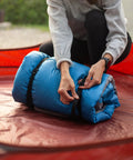 Two Pack 48 Inch Sleeping Bag Straps With Quick Release Buckles For Universal Fit securing blue sleeping bag outdoors.