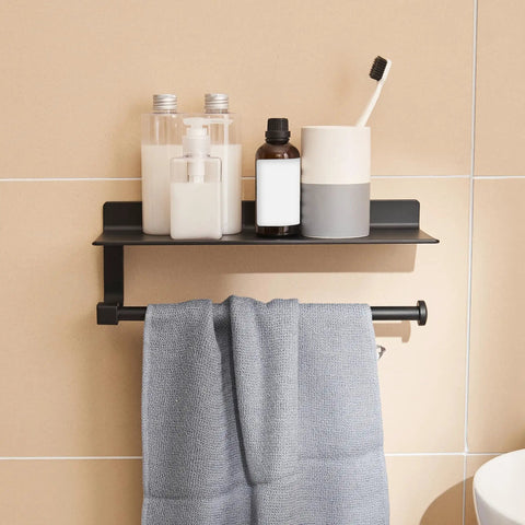 Black Wall Mount Towel Holder With Shelf For Bathroom And Kitchen, holding toiletries and a towel in modern beige tiled room.