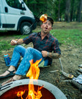 Man toasting marshmallow over campfire in forest while sitting on Lightweight Outdoor Chair For Stadium Seats Camping Hiking And More Water Resistant Adjustable Straps All Terrain Comfort Ultra Portable Go To Easy To Carry Built For Any Adventure Durable And Cozy Sit Anywhere.